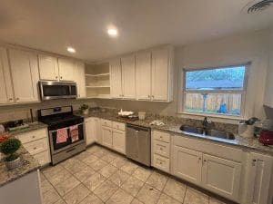 Freshly painted white kitchen cabinets with granite countertops, stainless steel appliances, and tile flooring