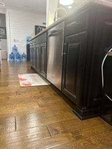 Freshly painted black kitchen cabinets with raised panel doors, brushed nickel handles, stainless dishwasher, and hardwood flooring
