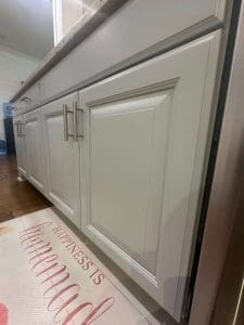 Freshly painted white kitchen cabinets with raised panel doors and brushed nickel bar handles