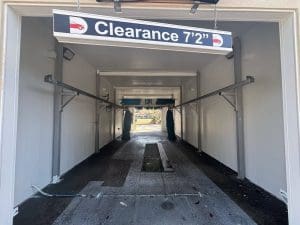 Entrance to an automatic car wash bay with a 7 foot 2 inch clearance sign and freshly painted light gray walls