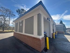 Freshly painted Charleston SC commercial building exterior with gray stucco, cream trim, and red brick base