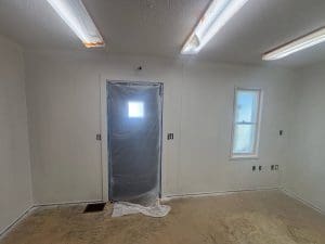 Charleston SC interior painting project in progress with plastic-masked door, light fixtures, and window in primed room