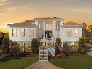 Freshly painted Charleston SC luxury home exterior with white stucco, elevated porch, and grand staircase at sunset