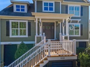 Freshly painted Charleston SC two-story home exterior with green siding, white trim, and elevated front porch