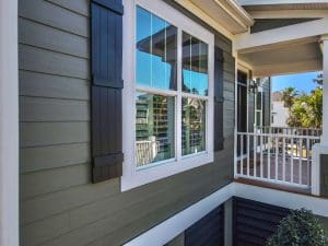 Freshly painted Charleston SC home exterior with green lap siding, white trim, and black board-and-batten shutters