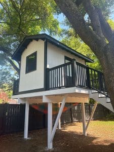 Freshly painted Charleston SC backyard playhouse with white siding and black trim