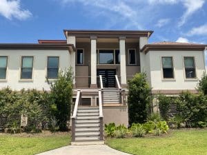 Freshly painted Charleston SC two-story home exterior with cream stucco, brown trim, and elevated front staircase
