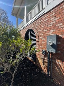 Charleston SC home exterior with red brick base, white porch railings, and freshly painted black arched louver vent