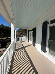 Freshly painted Charleston SC porch with white siding, black shutters, white railings, and pale blue ceiling