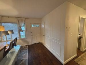 Freshly painted Charleston SC entryway with cream walls, white picture-frame wainscoting, and dark hardwood floors