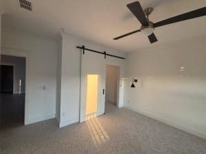 Freshly painted Charleston SC bedroom with crisp white walls, white barn door, and carpet flooring