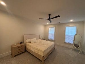 Freshly painted Charleston SC bedroom with warm cream walls, white trim, and carpet flooring