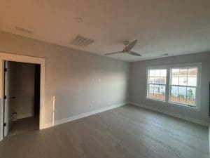 Freshly painted Charleston SC bedroom with soft gray walls, white trim, and hardwood floors