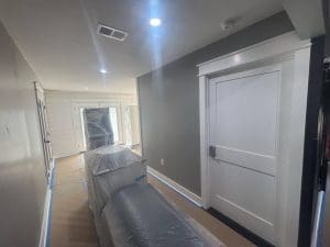 Charleston SC interior painting project with freshly painted gray walls, white door, and furniture covered for protection