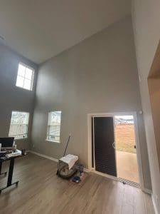 Freshly painted Charleston SC living room with greige walls, tall vaulted ceiling, and patio sliding door