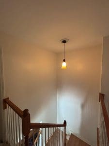 Freshly painted Charleston SC stairwell with tall cream walls, white spindles, and wood railings