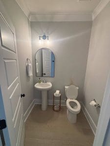 Freshly painted Charleston SC powder room with soft gray walls, white trim, and pedestal sink