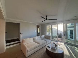Freshly painted Charleston SC living room with warm gray walls, white sofa, and patio sliding doors