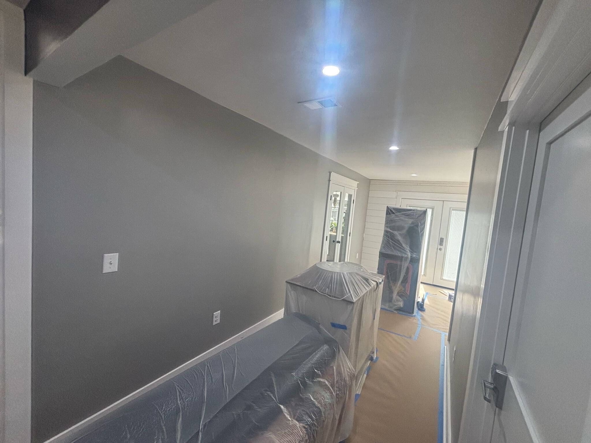 Charleston SC interior painting project with freshly painted gray walls and furniture covered in protective plastic