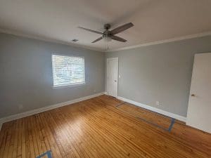 Freshly painted Charleston SC bedroom with soft gray walls, white trim, and hardwood floors