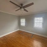 Freshly painted Charleston SC bedroom with soft gray walls, white trim, and hardwood floors