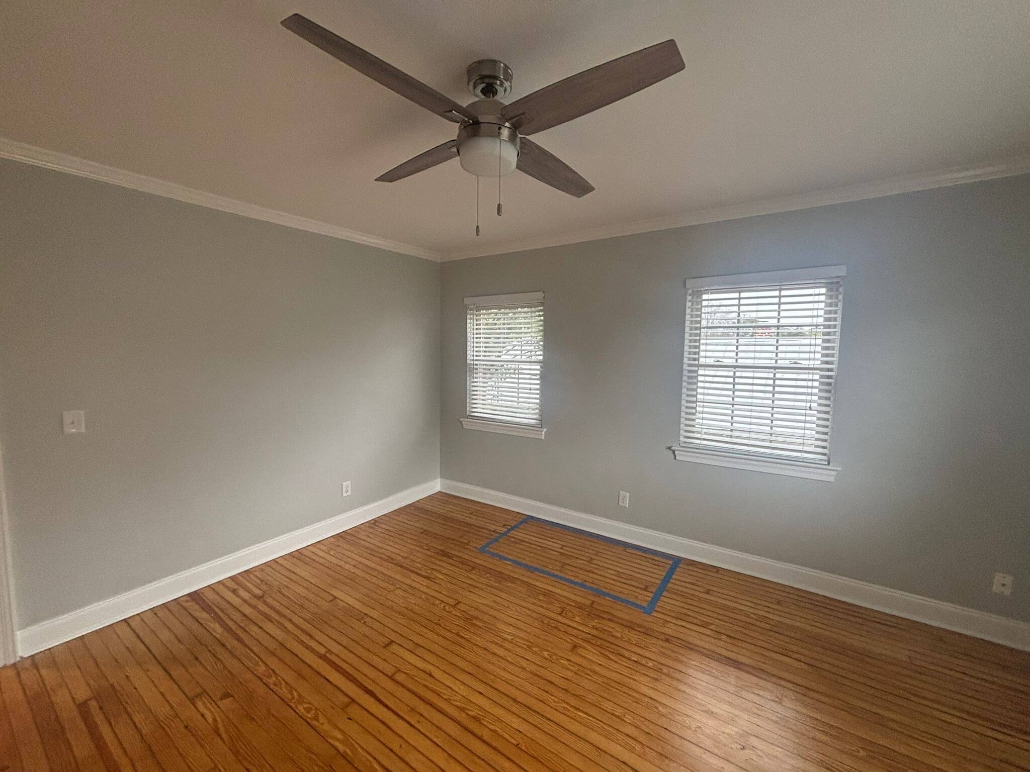 Freshly painted Charleston SC bedroom with soft gray walls, white trim, and hardwood floors