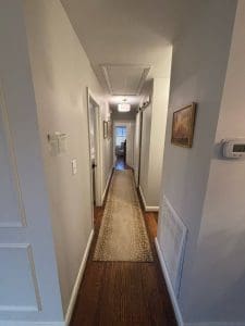 Freshly painted Charleston SC hallway with soft gray walls, white trim, and dark hardwood floors