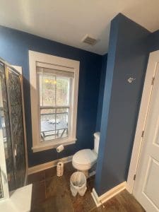 Freshly painted Charleston SC bathroom with deep navy blue walls, white trim, and tile flooring