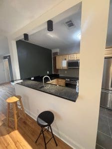 Freshly painted Charleston SC kitchen with cream walls, dark green accent wall, and breakfast bar