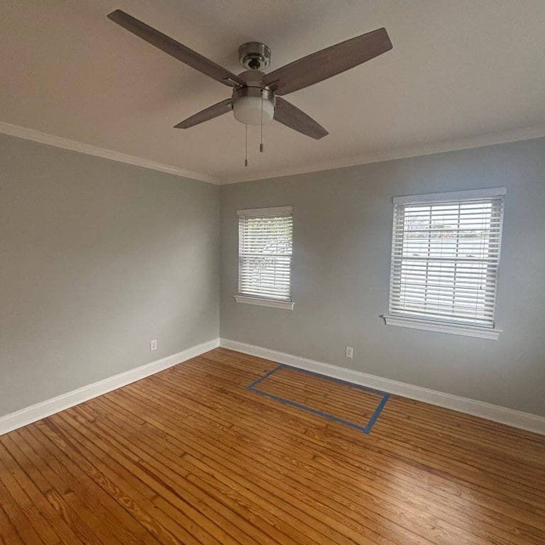 Freshly painted Charleston SC bedroom with soft gray walls, white trim, and hardwood floors